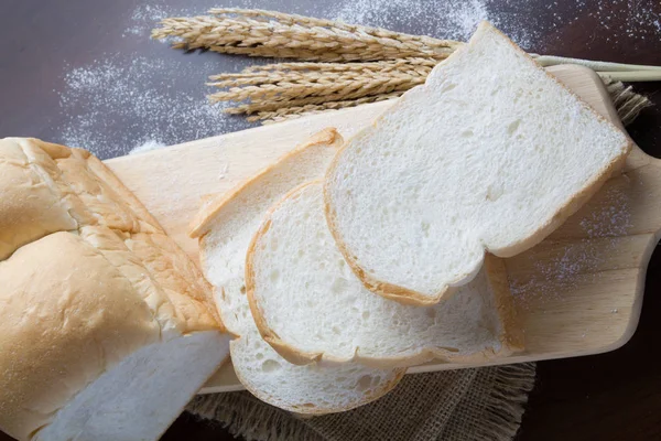 Pão com espigas de trigo na tábua escura — Fotografia de Stock