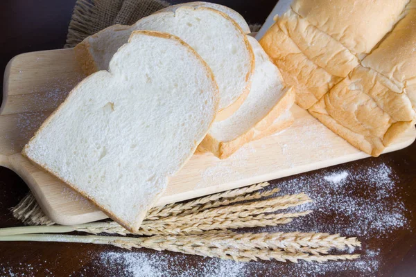 Pão com espigas de trigo na tábua escura — Fotografia de Stock
