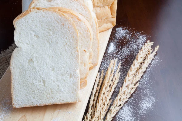 Pão com espigas de trigo na placa escura com farinha — Fotografia de Stock