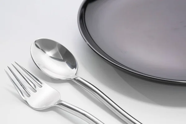 Black plate with fork and spoon isolated — Stock Photo, Image