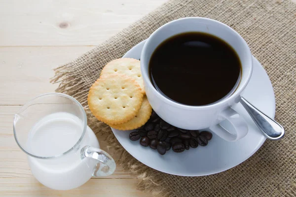 Xícara de café e leite com biscoito na mesa de madeira — Fotografia de Stock