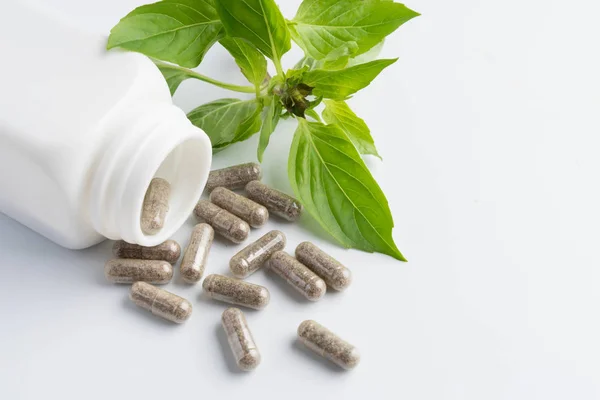 Herb capsules spilling out of a bottle isolated — Stock Photo, Image