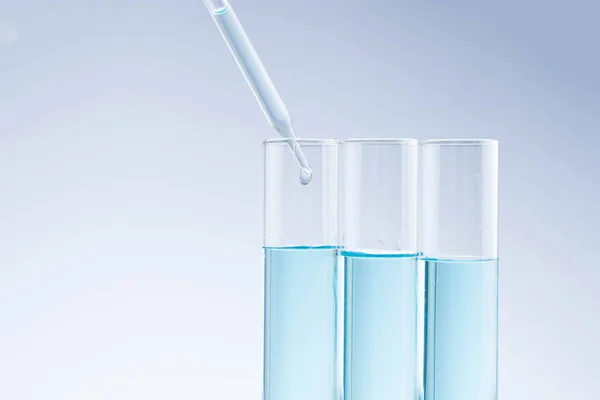 Laboratory close up of a pipette dropping sample into — Stock Photo, Image