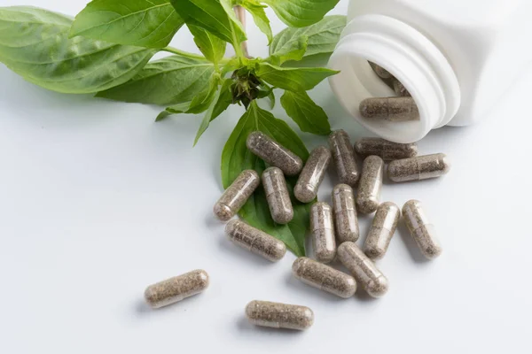 Herb capsules spilling out of a bottle isolated — Stock Photo, Image