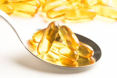 Balık yağı kapsülleri bir kaşık beyaz arka plan üzerinde