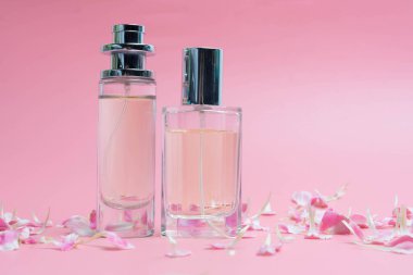 Parfüm şişeleri ve pembe arka plan üzerinde gül