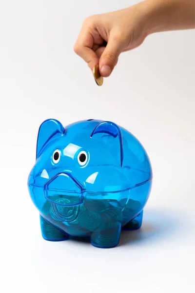 Mão de banco porquinho azul colocando moeda no branco — Fotografia de Stock
