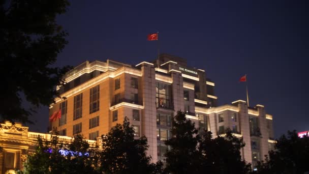Knipperende rode Chinese vlaggen op het schiereiland Hotel, Shanghai Bund 's nachts — Stockvideo