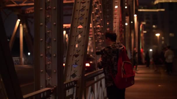 Hombre fotógrafo tomando fotos de coches en el puente brillantemente iluminado en la noche 4k — Vídeos de Stock