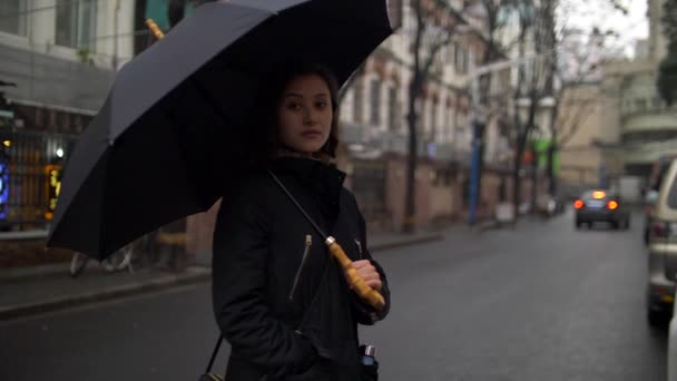 Schöne junge Frau mit einem Regenschirm auf der Straße an einem kalten Tag slo mo — Stockvideo