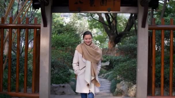 Attraktive junge gemischte Frau geht durch die Tore im chinesischen Stil und lächelt 4k — Stockvideo