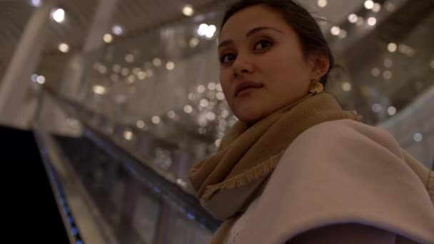 Attraktive junge gemischte Frau steht auf Rolltreppe Nahaufnahme bokeh 4k — Stockvideo