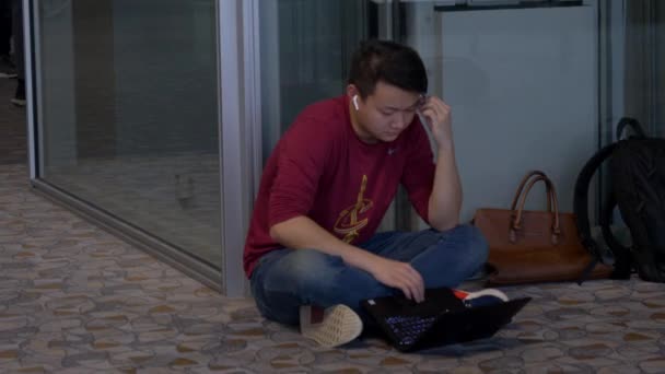 Asijský člověk sedí na podlaze na letišti v Šanghaji Pudong pomocí notebooku čeká — Stock video