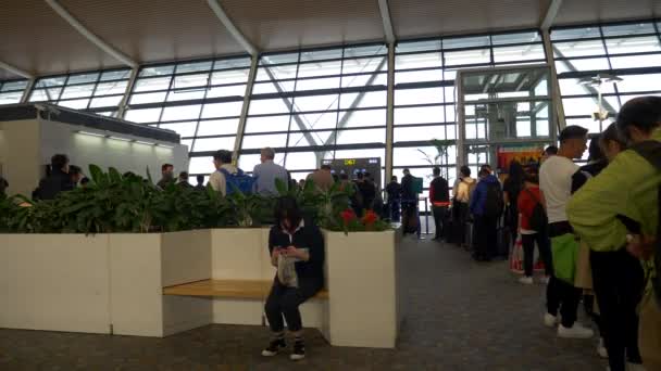 Woman Sits on Bench Waiting by Boarding Line at Shanghai Pudong Airport — Stock Video