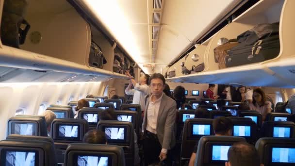 Uçağın içindeki yolcular koltukları arasın, raflara bir şeyler koysunlar. — Stok video