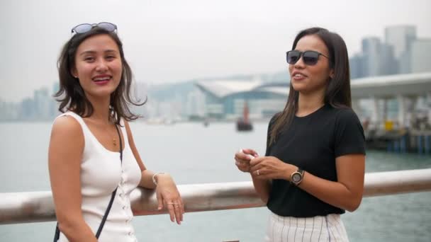 Gyönyörű fiatal ázsiai nő tesz ajakbalzsam hallgat barát és nevetés — Stock videók
