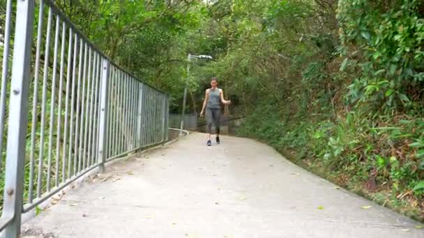 Bella ragazza mista in abiti da allenamento cammina attraverso il ponte e sorride — Video Stock