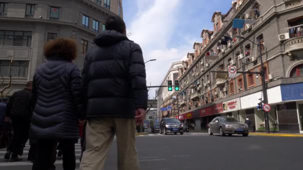 Ludzie przejeżdżają przez ulicę na Zebrze z samochodami jadącymi obok w Szanghaju — Wideo stockowe