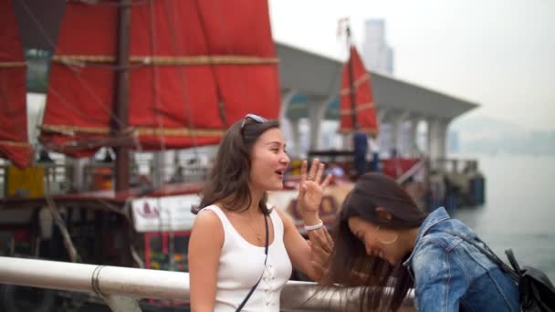 Young Women Talk by Pier Laughing Hard with the Boat with Red Sails Behind — 비디오