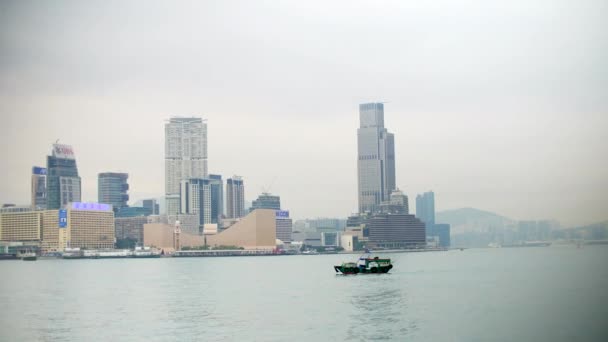 Piccola barca di Hong Kong sulla baia di Victoria con edifici alle spalle, 4k — Video Stock