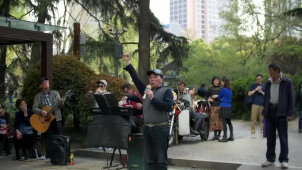 Eldre kinesiske menn synger og spiller musikkinstrumenter i Shanghai Jingan Park 4k – stockvideo