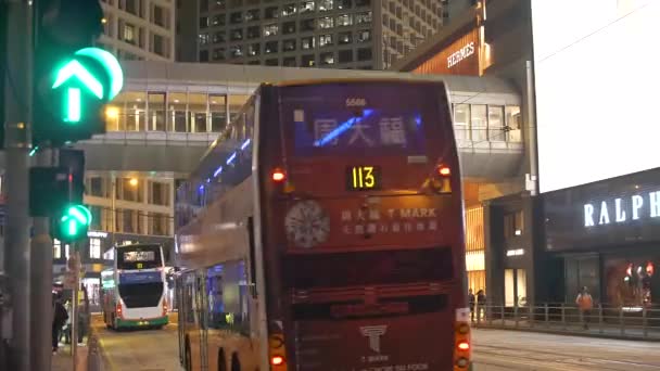 Улица Гонконга ночью с автобусами, проезжающими мимо 4K — стоковое видео