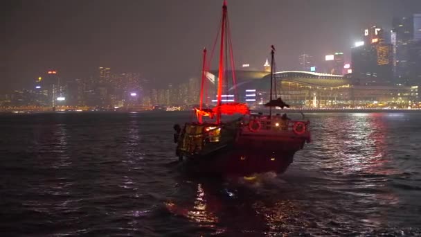 Ярко освещенная лодка с красными парусами, уходящая в ночь в большом городе 4k — стоковое видео