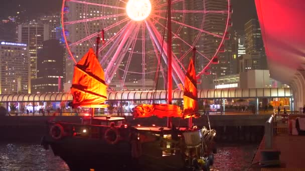 Barco Lit brillante con las velas rojas que acoplan por la rueda de la fortuna en la noche en una ciudad grande 4k — Vídeos de Stock