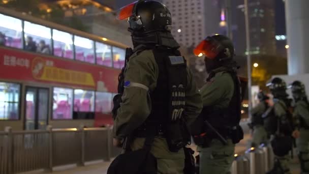 Группа тяжеловооружённых гонконгских спецназовцев стоит у оживлённой улицы ночью 4k — стоковое видео