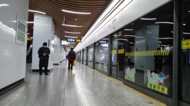 Tıbbi maske takan iki kişi Çin 'deki boş istasyonda treni bekliyor.