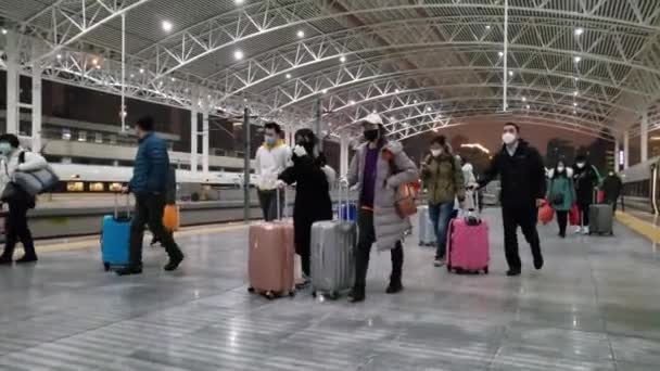 I cinesi con valigie che indossano maschere si allontanano dal treno in Cina — Video Stock