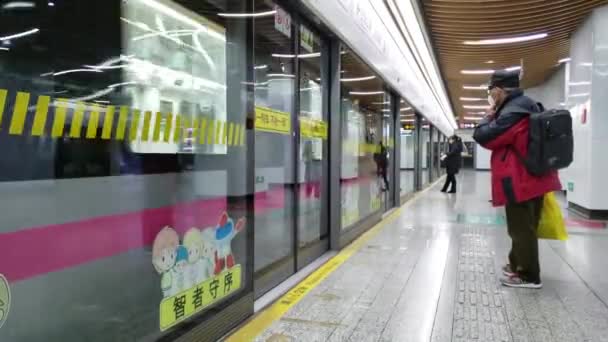 Metrotrein arriveert terwijl twee mensen het dragen van medische maskers wachten op het station — Stockvideo