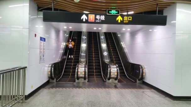Weinig gemaskerde mensen op lege metrostation roltrap in China als gevolg van quarantaine — Stockvideo