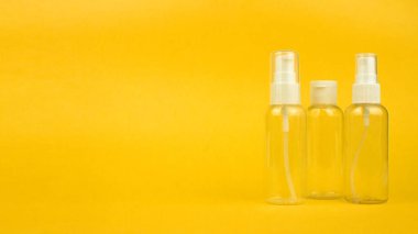 Pompalı boş plastik şişeler ve sarı arka planda fotokopi alanı olan sprey. Seyahat için temiz kozmetik kutuları kiti. Banner şablonu, reklam için maket, sosyal medya. Stok fotoğrafı.