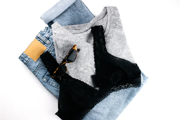 T-shirt de algodão cinza, jeans azul, soutien flat lay no fundo branco. Roupas em estilo mínimo. Roupa vintage simples vista superior. Modelo, mockup para publicidade, web, redes sociais. Foto stock . — Fotografia de Stock