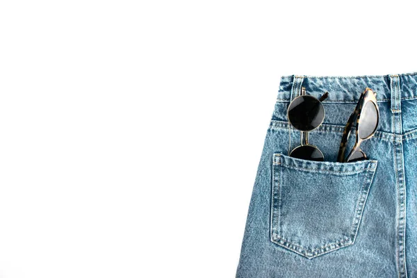 Modré unisexové džíny se slunečními brýlemi v kapse ležely izolované na bílém pozadí s kopírovacím prostorem. Každý den módní oblečení v minimálním stylu. Šablona, maketa pro web, reklama, sociální média. — Stock fotografie