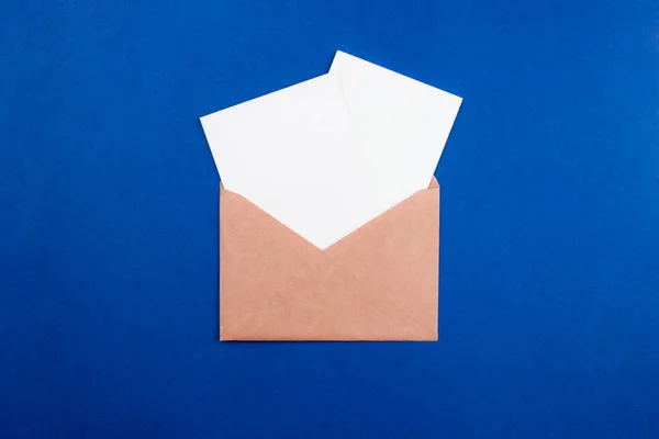 Envelop met witte papieren vellen letters plat lag op trendy kleurrijke blauwe achtergrond. Bovenaanzicht met kopieerruimte. Communicatie, abc concept. Minimale stijl template, model voor web, social media. — Stockfoto