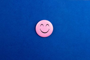 Renkli mavinin üzerinde pembe gülücük simgesi deseni vardı. Kopyalama alanı olan üst görünüm. Mutlu neşeli gülümseme emojisi. Web, sosyal medya ve reklamcılık için minimal biçim şablonu. Stok fotoğrafı.