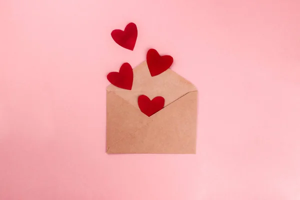 Rode harten vliegen uit ambachtelijke papieren envelop plat lag op kleurrijke roze achtergrond. 8 maart, Moederdag, Valentijnsdag te vieren. Bovenaanzicht met kopieerruimte. Template voor web, media. Voorraadfoto — Stockfoto