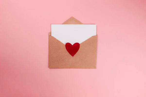 Liefdesbrief met wit vel papier in ambachtelijke papieren envelop met rood hart plat lag op kleurrijke roze achtergrond. 8 maart, moederdag, Valentijnsdag sjabloon. Bovenaanzicht met kopieerruimte. Voorraadfoto — Stockfoto