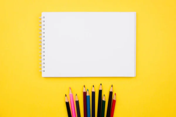 Sketchbook, notebook and color pencils flat lay on colorful yellow background. Top view with copy space. School and office supplies layout. Back to school concept. Template for web. Stock photo. — Stock Photo, Image