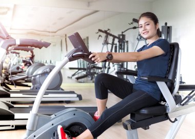 Asyalı kadın binicilik sabit bisiklet içinde jimnastik salonu.