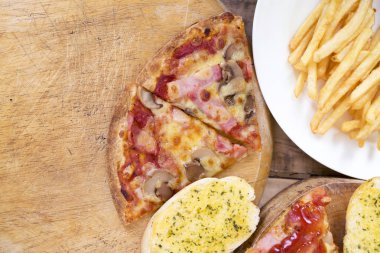 Fast food, çıtır tavuk kanatları, ekmek, patates kızartması ve pizza üzerinde 