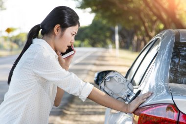 Araba petrol aşağı ve genç kadın üzerinde telefon yardım çağırmak için çalışıyor