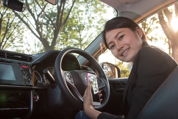 Mujer de negocios sostiene un teléfono inteligente en coche moderno . —  Fotos de Stock