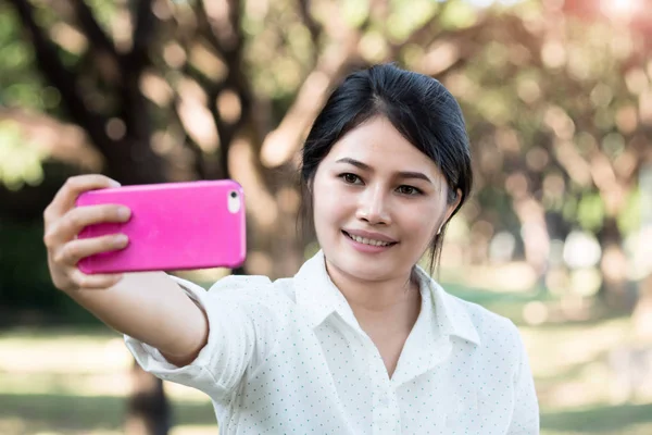 Portræt af en smuk asiatisk ung kvinde selfie i parken Vid - Stock-foto