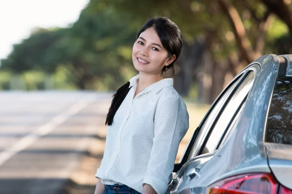 Asiático jovem mulher de pé, descansando ao lado de seu carro — Fotografia de Stock
