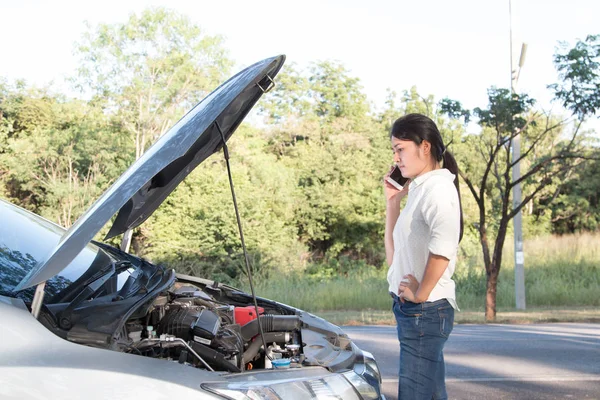 Asian young woman looking at broken down car engine on street. O — Stock Photo, Image