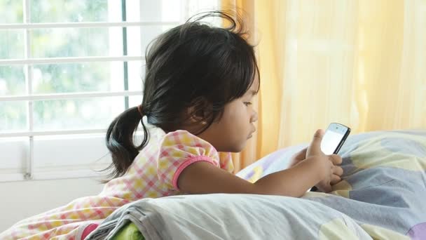 Menina asiática jogando smartphone em casa . — Vídeo de Stock