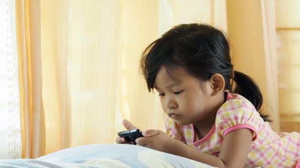 Menina asiática jogando smartphone em casa . — Vídeo de Stock